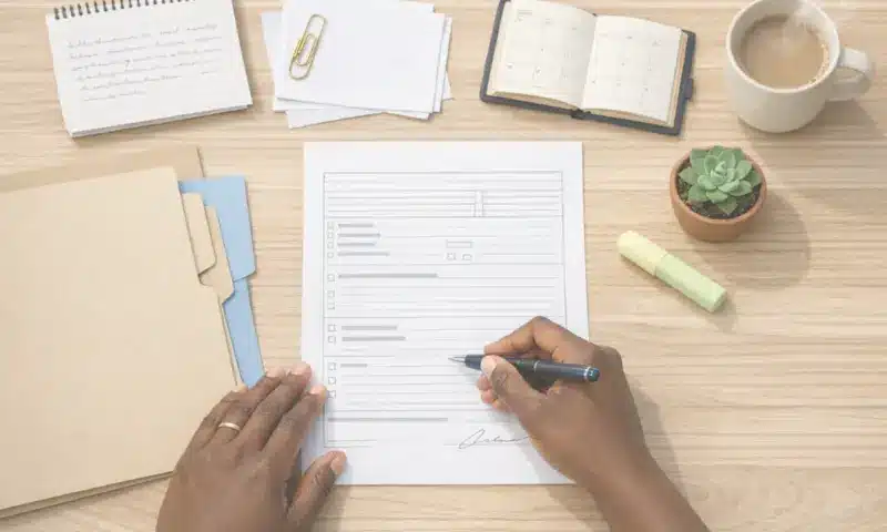 Mains remplissant un formulaire administratif – aide à la rédaction des directives anticipées et organisation des démarches de fin de vie par Stecy, doula dans les Yvelines (78)