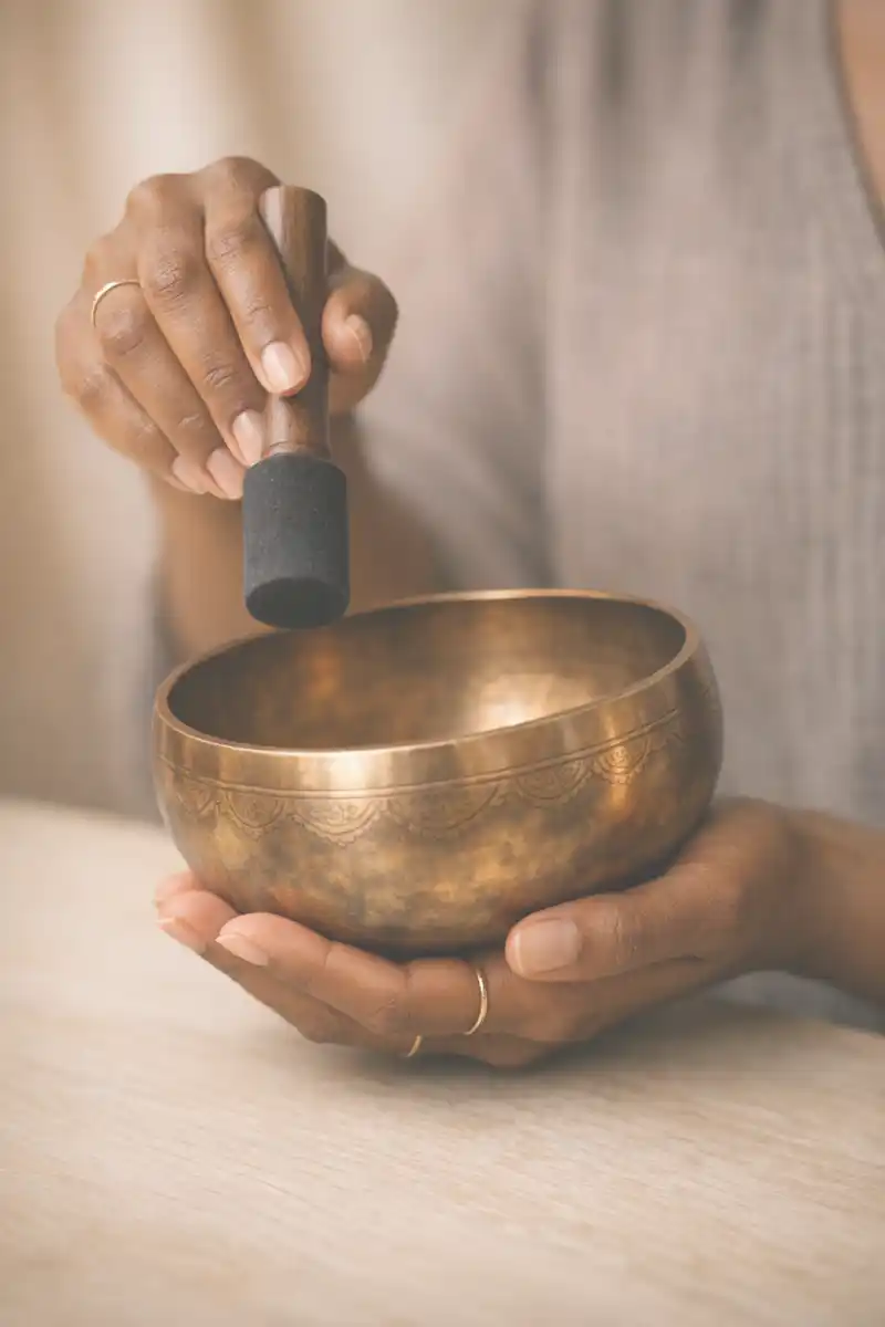 Bol chantant tibétain tenu dans les mains d'une doula de fin de vie lors d'une séance de sonothérapie – accompagnement palliatif dans les Yvelines